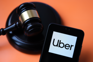 Uber logo seen on smartphone and judge gavel on the blurred background. Concept for court ruling, Uber driver rights by Supreme court. United Kingdom. Uber UK Insurance Policies