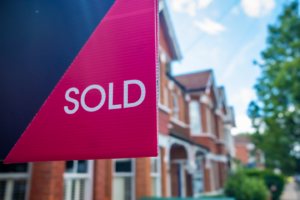 Stamp duty landlords UK. Estate agent SOLD sign with defocussed street of houses in background